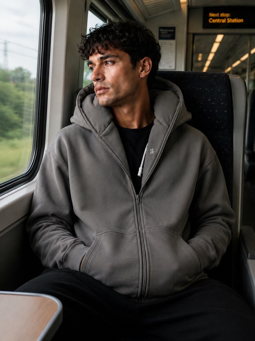 Man wearing a hoodie sitting on a train seat during travel